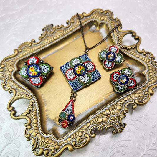 mosaic brooches and a necklace on a gold tray