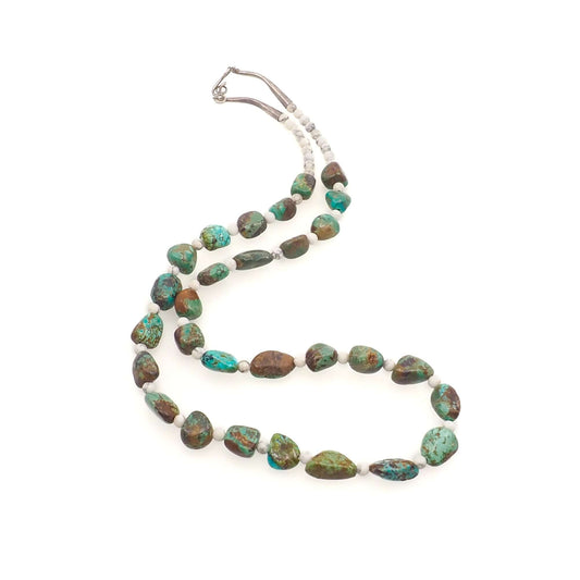 A vintage 1970s necklace with blue and green turquoise nuggets, round white howlite beads, and sterling silver beads.