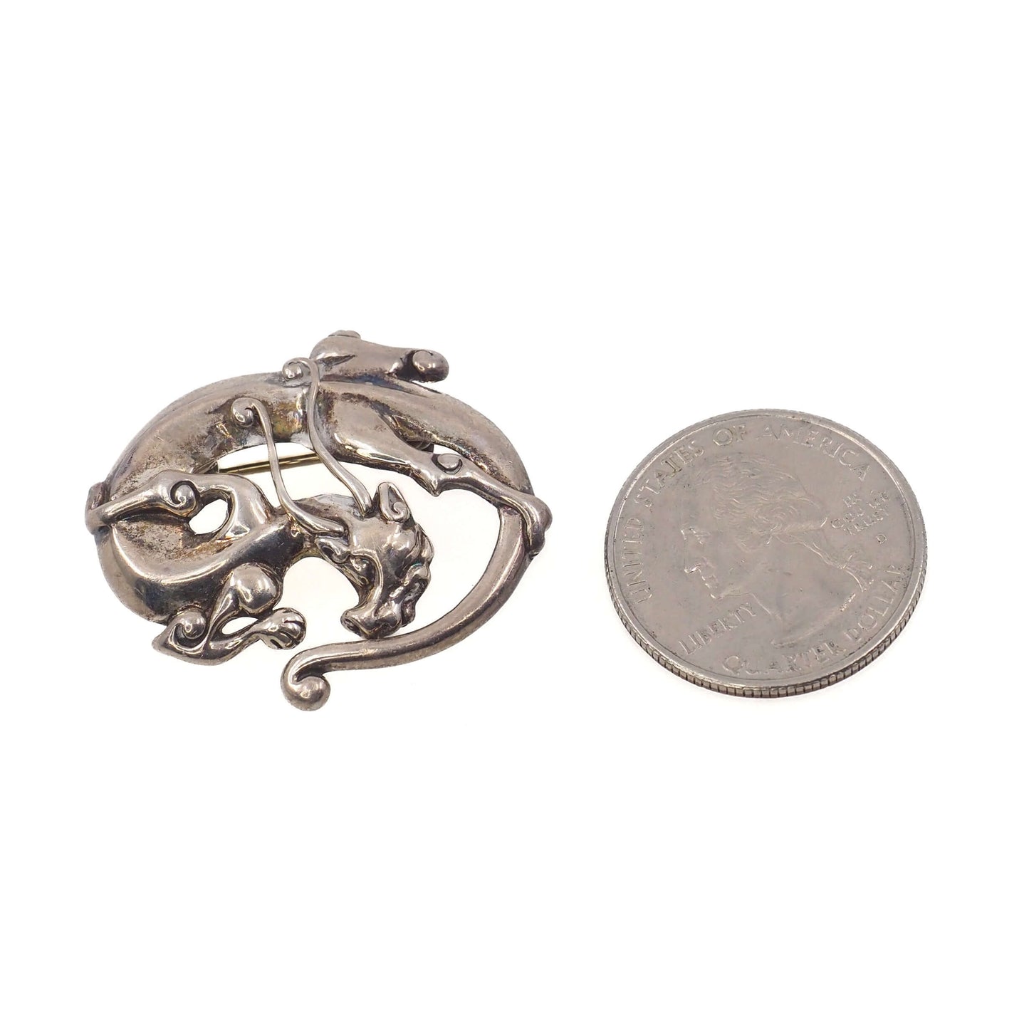 Sleeping Dragon Animal Figural Sterling Silver Brooch next to a quarter.