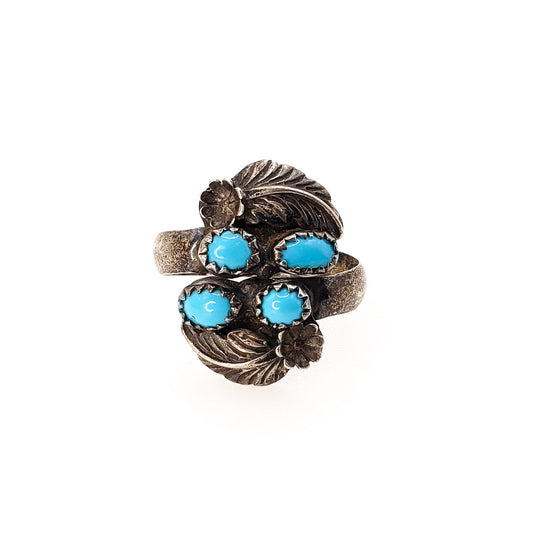 A vintage sterling silver ring with blue turquoise cabochons and feather accents, adjustable shank.