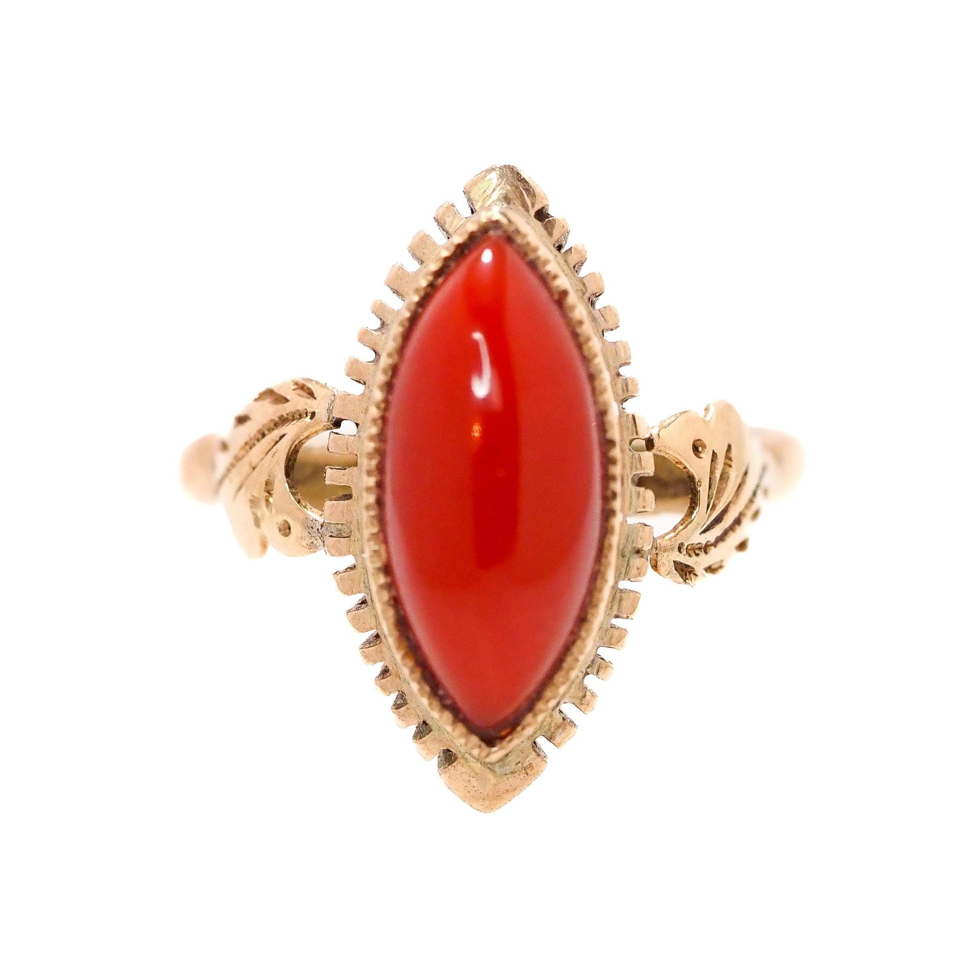 An antique mid-Victorian ring with a red marquise Sardinian coral set in 18K yellow gold, featuring intricate designs around the stone.