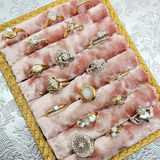 a pink velvet tray outlined in gold with an assortment of rings 