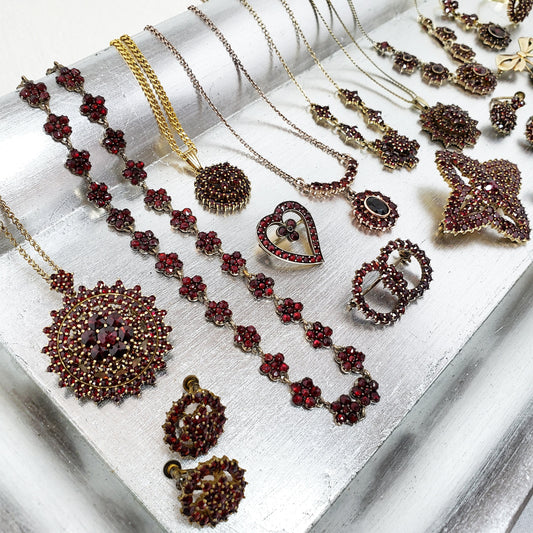 A silver tray full of red Bohemian garnet jewelry