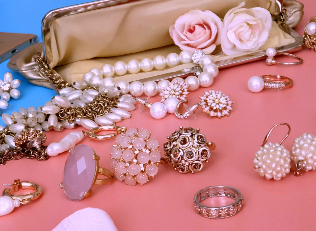 Pink costume jewelry spilling out of a purse on a pink background