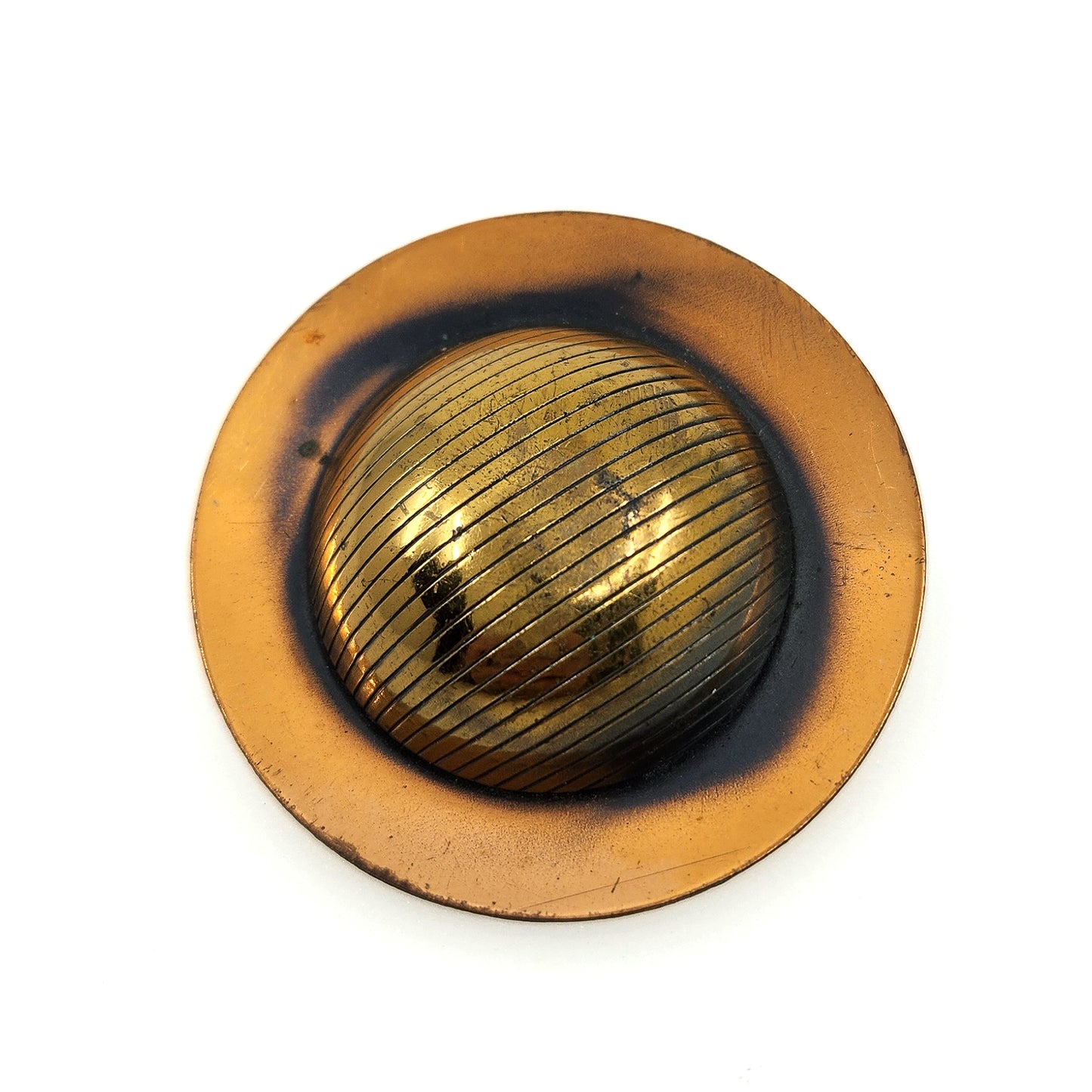 A vintage circular metal button or knob with a textured, ribbed golden center and a wider, flat bronze-toned outer ring, shown on a plain white background.