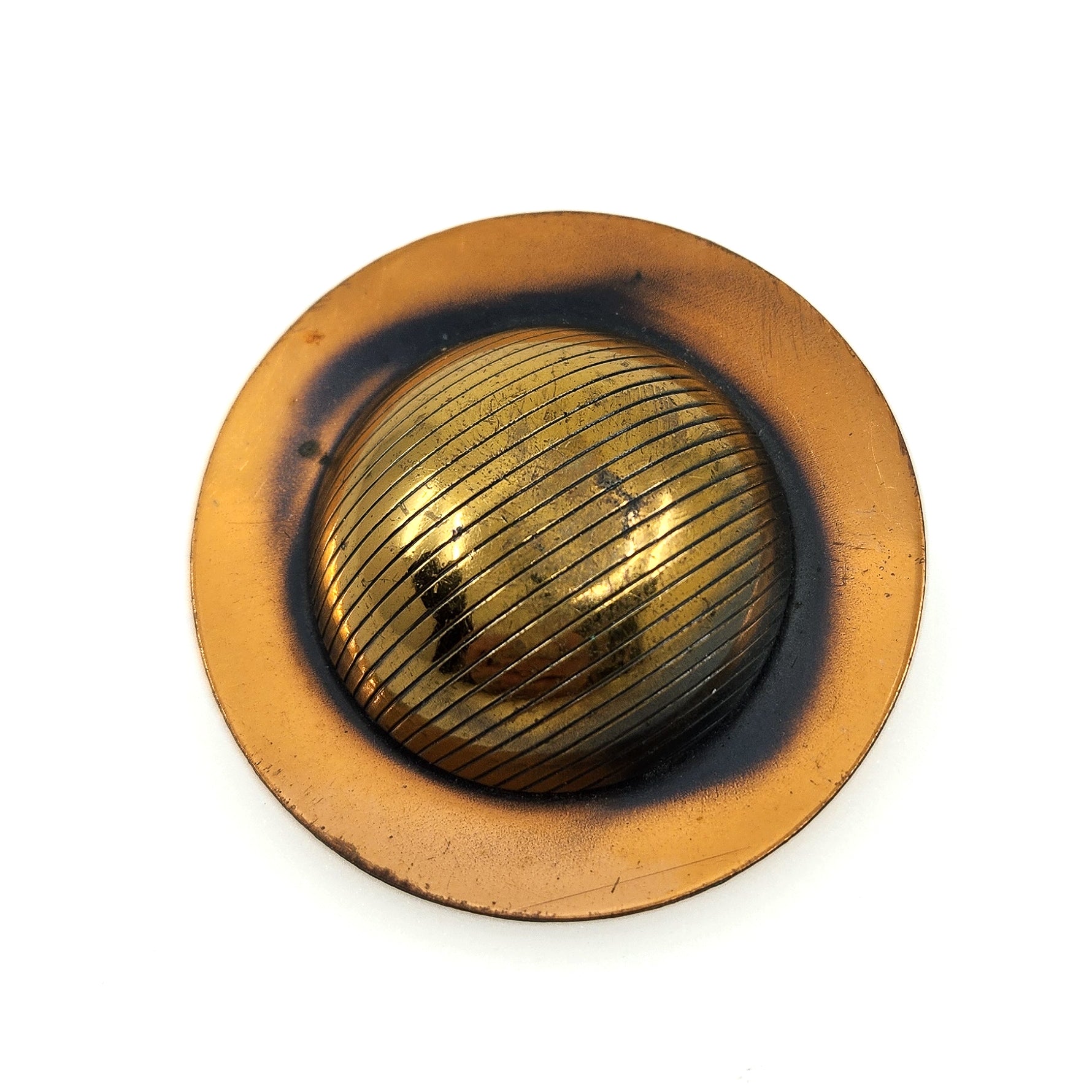 A vintage circular metal button or knob with a textured, ribbed golden center and a wider, flat bronze-toned outer ring, shown on a plain white background.