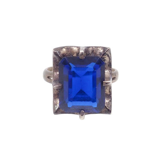 Ring with a blue gemstone and silver band on a white background