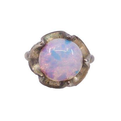 Ring with a round opal stone and metallic band on a white background