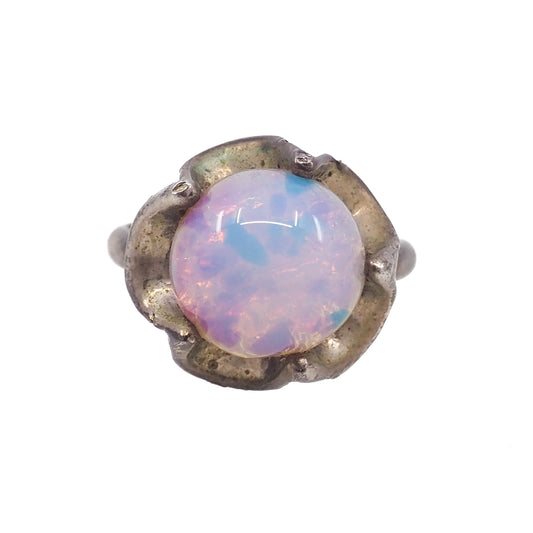 Ring with a round opal stone and metallic band on a white background
