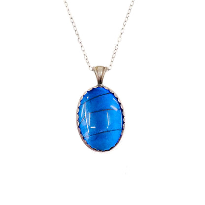 an oval blue pendant necklace with butterfly wing