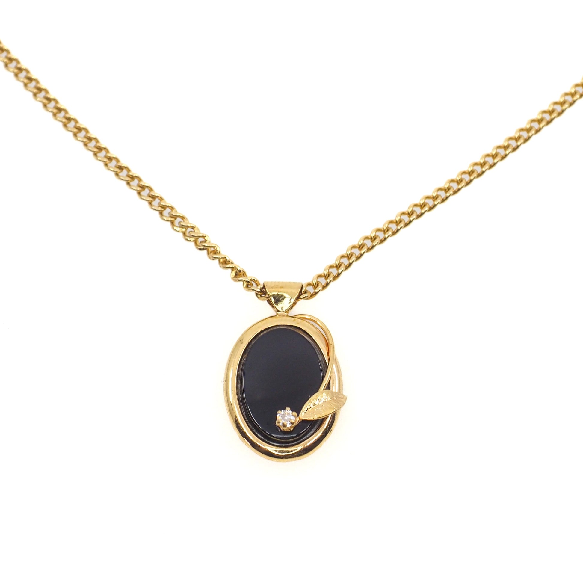 Gold necklace with a black pendant on a white background