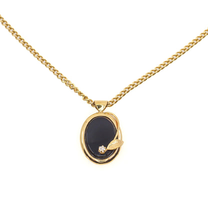 Gold necklace with a black pendant on a white background