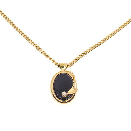 Gold necklace with a black pendant on a white background